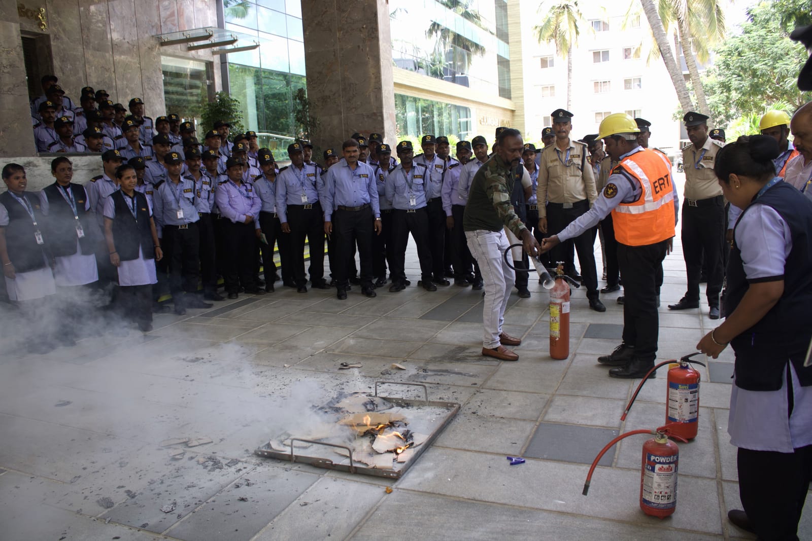 SDC guards with extinguishers at a live fire drill, an instructor in a high-visibility vest beside them