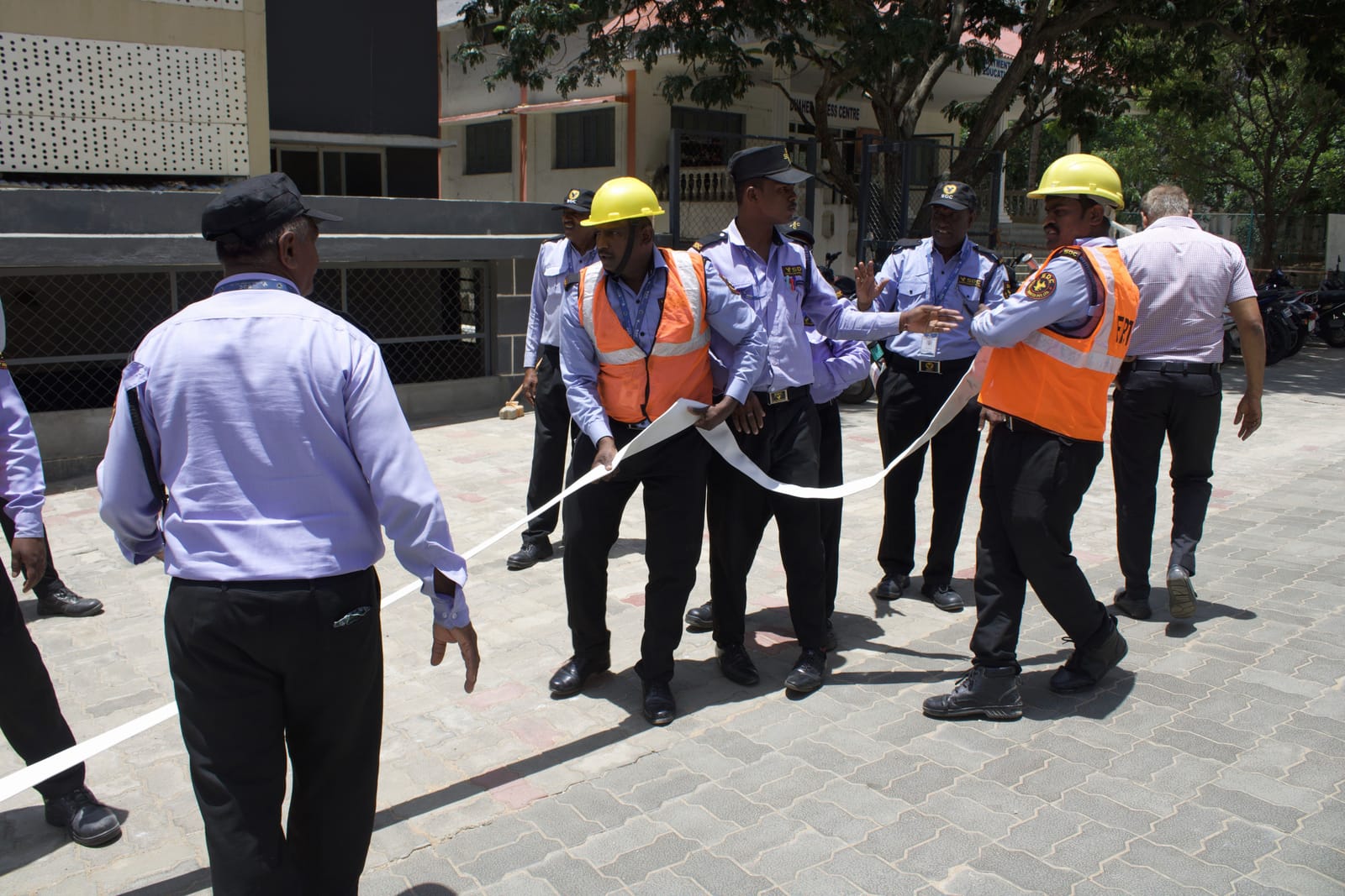 SDC guards in helmets and high-visibility vests running out a fire hose